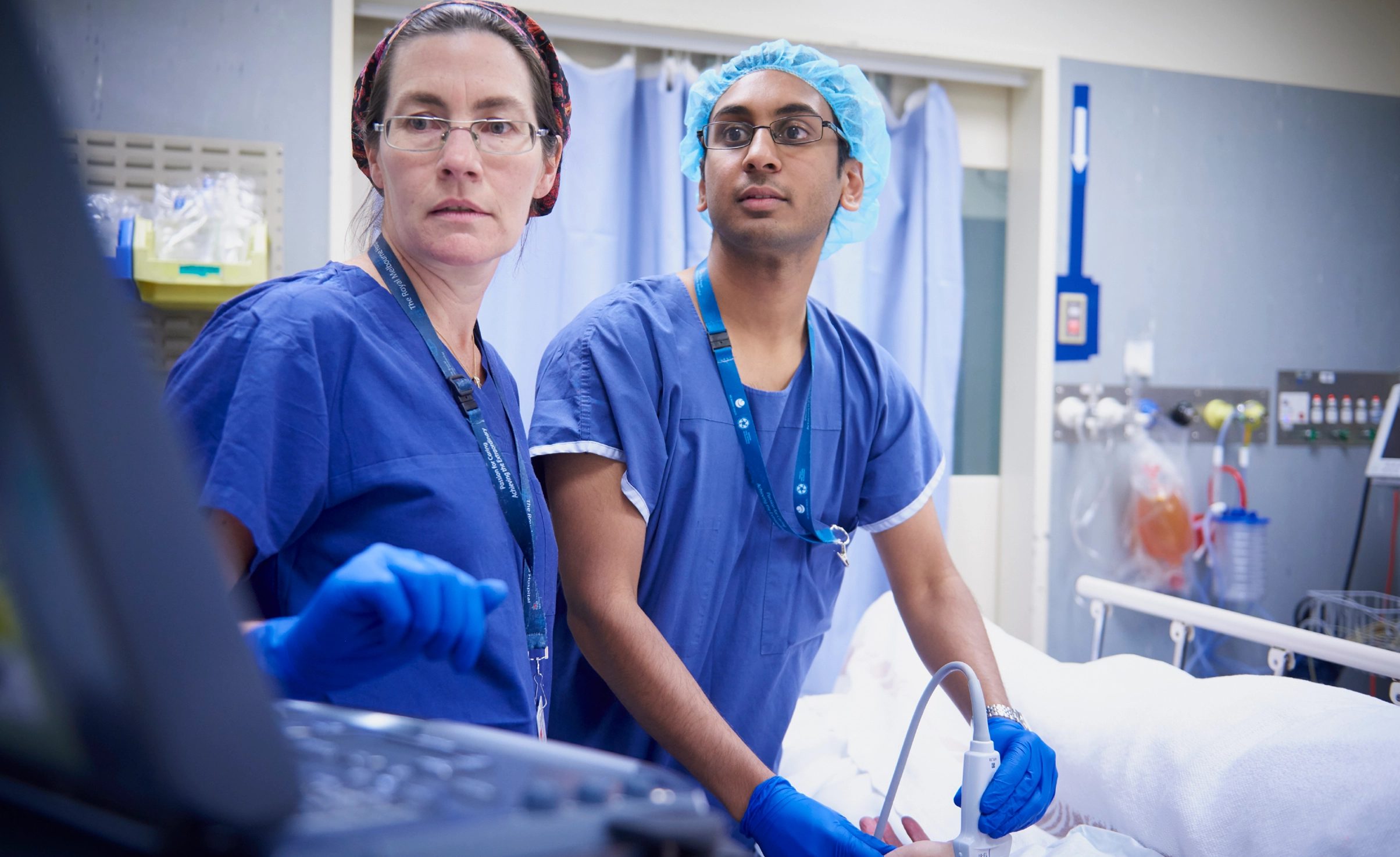 Two people in scrubs using ultrasound machine on patient and looking at monitor