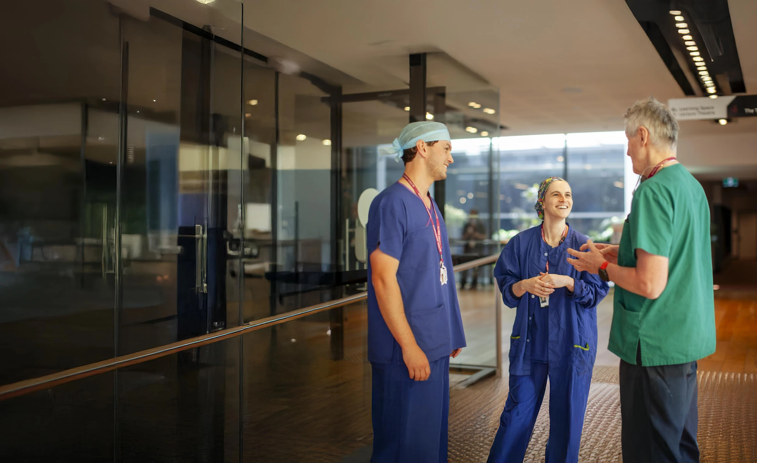 Three anaesthetists standing in a hospital reception talking 