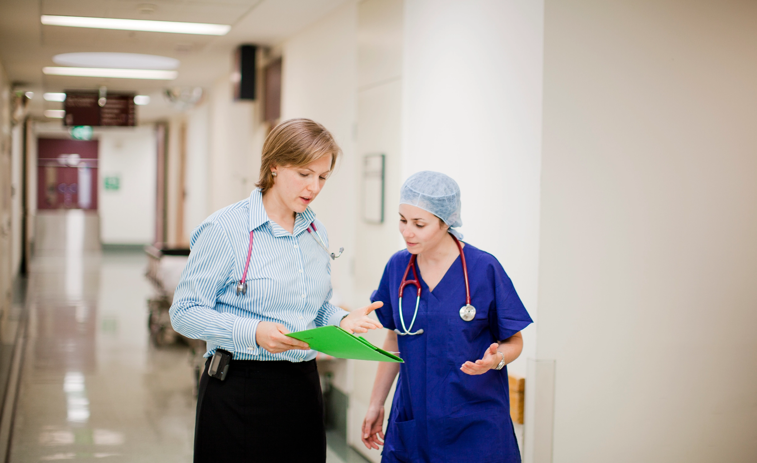 A senior female doctor discusses a chart with a junior doctor