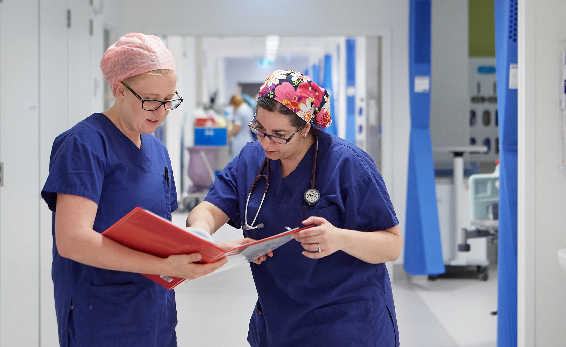 Two female doctor's looking at a chart in a hospital corridor